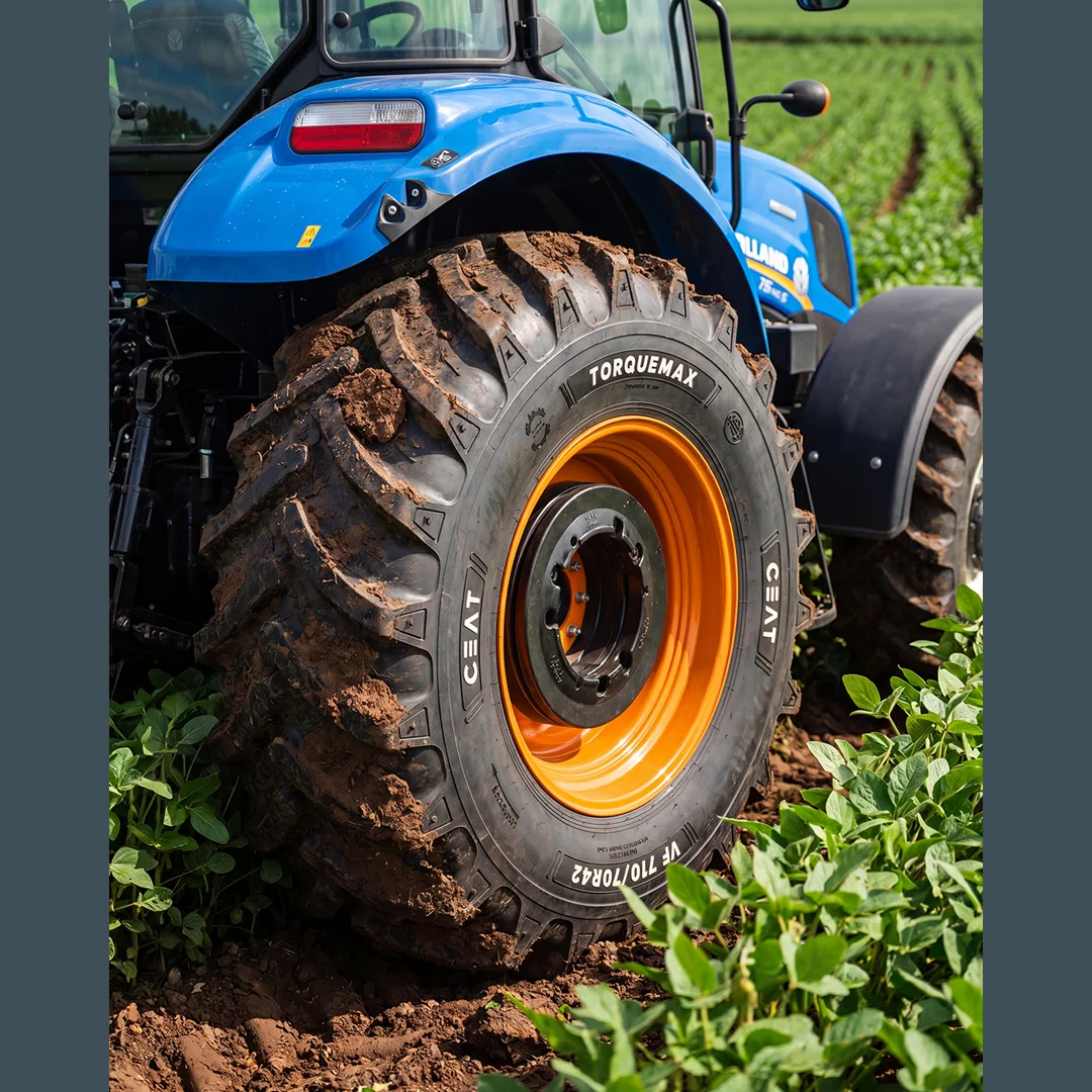 Trator azul em lavoura de soja com pneu agrícola CEAT Torquemax de aro laranja coberto de barro