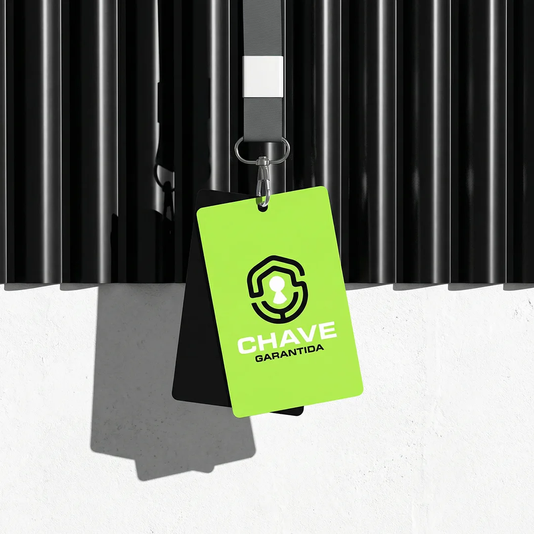 Crachá verde-lima da Chave Garantida pendurado em cordão, contra parede ripada preta