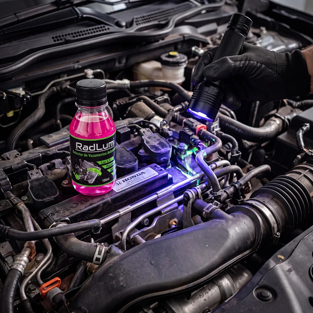 Lanterna UV revelando traços fluorescentes do RadLumi no cofre do motor, com o frasco do produto em primeiro plano